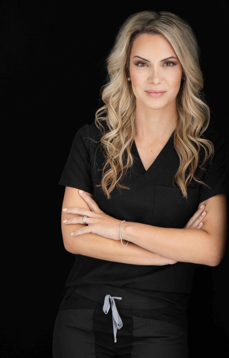 Female professional wearing scrubs, arms crossed.