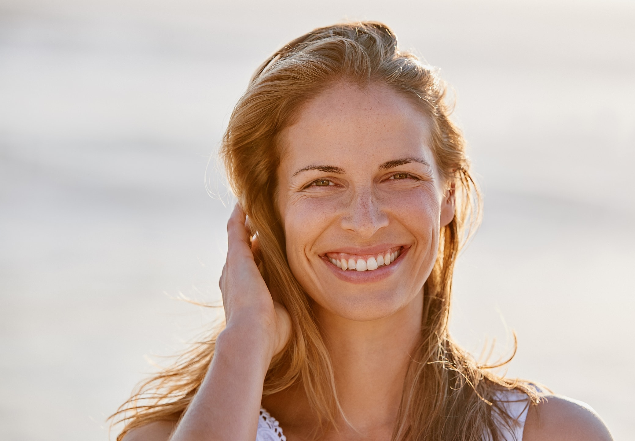Smiling woman enjoying sunny outdoor setting.